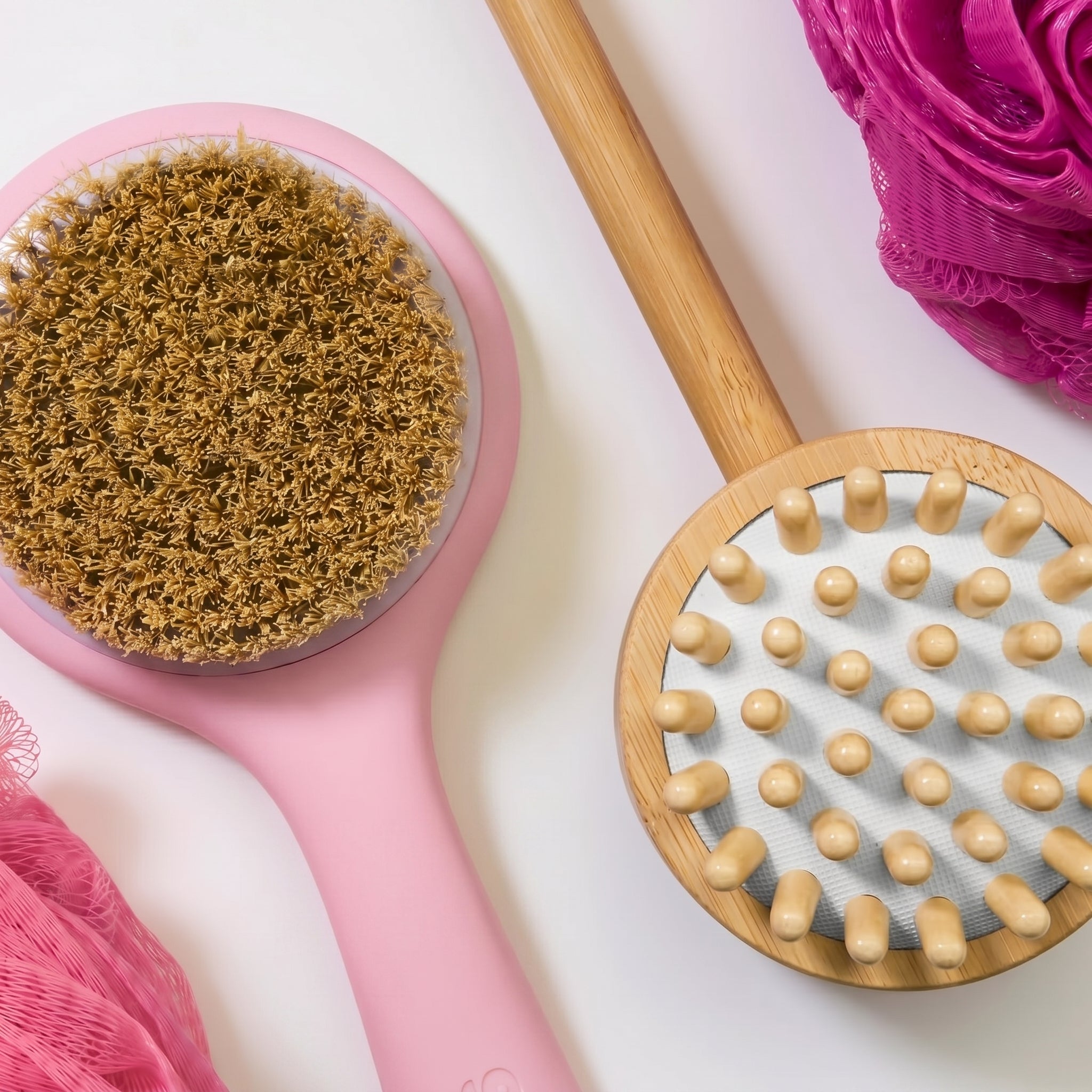 Two massage brushes, one pink with a textured head and one wooden with raised nodes, on a white background.